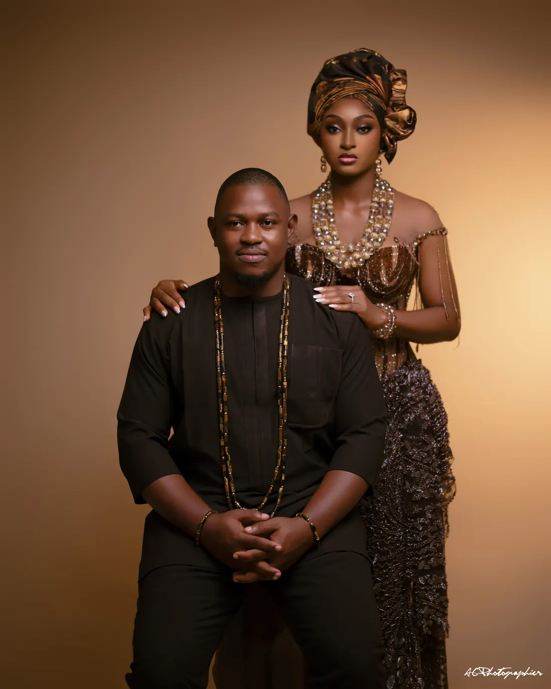 Kelvin seated with Emma standing beside him in traditional attire